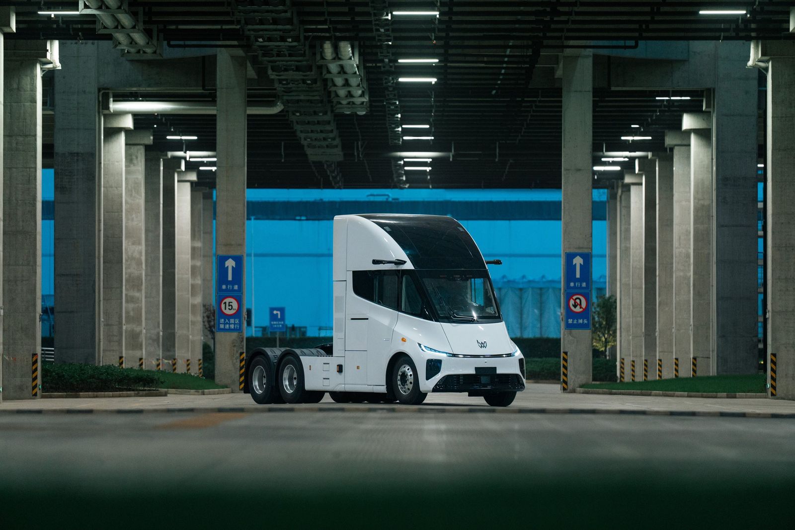 Un tractocamión eléctrico Xos blanco bajo un paso a desnivel de concreto